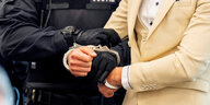 Eine Person wird von jemandem in Justizuniform in Handschellen gelegt