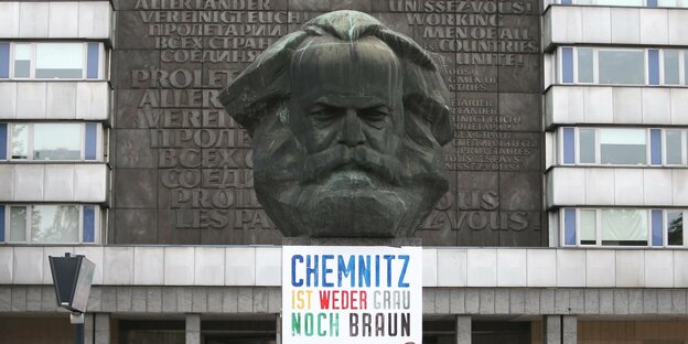Eine Statue von Karl Marx, darunter steht auf einem Schild: Chemnitz ist weder grau noch braun