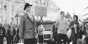 Ein Mann hält ein Schild: "Vielfalt statt Einfalt für Weltoffenheit". Im Hintergrund tanzen Menschen