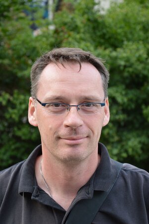 Ein Mann mit randloser Brille und Polohemd lächelt in die Kamera Ein Mann mit randloser Brille und Polohemd lächelt in die Kamera