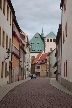 Eine Stadtansicht aus Freiberg in Sachsen. Schmucke restaurierte Häuser. Im Hintergrund der Dom. Nur ein Auto parkt in der Straße, menschen sind keine zu sehen