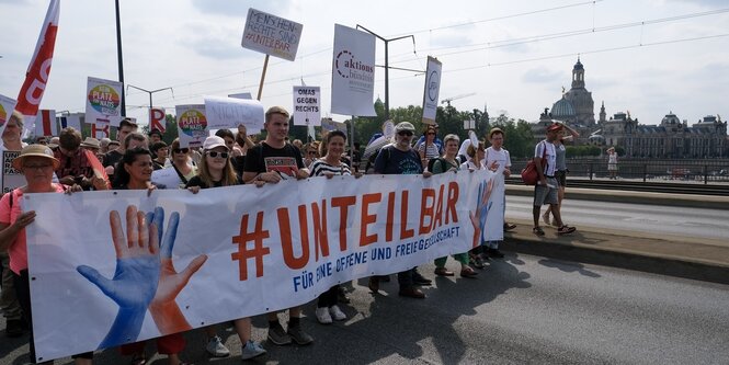 Unteilbar steht auf einem Transparent, das Menschen vor sich her tragen, die über eine Elbbrücke gehen