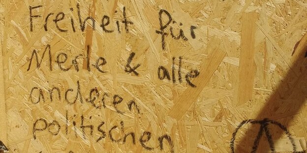 auf einer Holzplatte steht „Freiheit für Merle und alle anderen Politischen“
