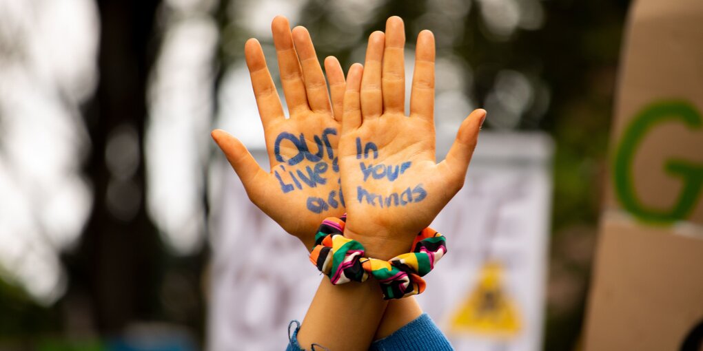 Zwei Hände, überkreuz ausgestreckt. In den Handflächen steht : Our lives are in our hands