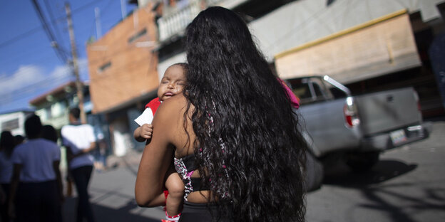 Eine Frau trägt ein Baby im Arm