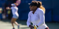 Serena Williams mit Schläger in weißem Tennisoutfit auf dem Spielfeld