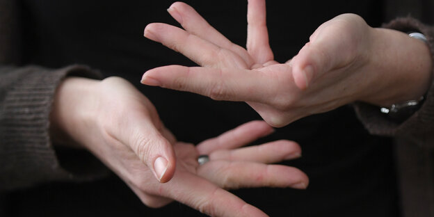 Zwei Hände mit gespreizten Finden zeigen ein Wort in Gebärdensprache