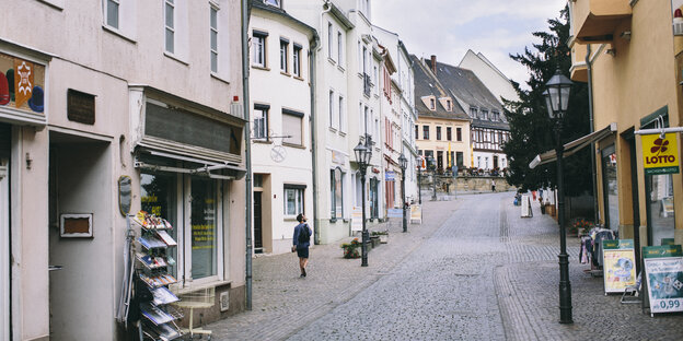 Eine beschauliche Straße einer Kleinstadt, rechts ein Kiosk, links ein anderer Kleinwarenladen