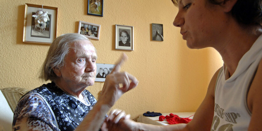 Hör-/sehbehinderte Frau kommuniziert mit Mitarbeiterin