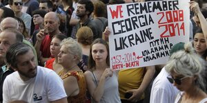 Demonstranten, eine Frau hält ein Transparent auf dem steht: We remember georgia 2008 Ukraine 2014
