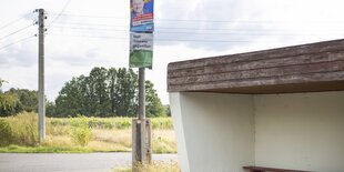 Bushäuschen aus Beton, daneben Wahlwerbung