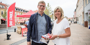 Mann und Frau verteilen Flugblätter. Es sind Sebastian Walter und Kathrin Dannenberg von der Linken