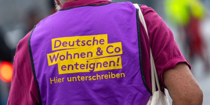 Mann mit Weste und Aufschrift "Deutsche Wohnen enteignen"