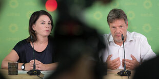 Annalena Baerbock und Robert Habeck sitzen nebeneinander an einem Tisch