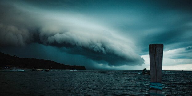 Düstere Wolken brauen sich in einem Sturm über einem Küstenstreifen zusammen