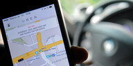 Ein Fahrer hat in seinem Fahrzeug die Uber-App auf seinem Smartphone geöffnet
