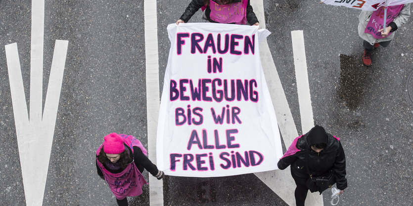 Frauen tragen ein Transparent mit der Aufschrift "Frauen in Bewegung bis wir alle frei sind"