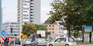 Das Bild zeigt eine Straße mit Autos und ein Hochhaus dahinter. An der Wand des Hochhauses hängt ein Banner mit der Aufschrift "Chemnitz, Sachsen, Weltoffen"