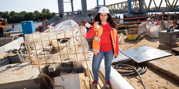 Frau in Warnweste und Helm auf einer Baustelle