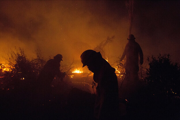 Feuerwehrmänner kömpfen gegen einen Waldbrand in Bolivien an. Es ist Nacht, nur das Feuer ehellt die Szenerie