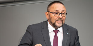 Frank Magnitz im dunklen Anzug und roter Krawatte mit Brille und Bart spricht