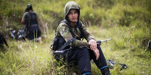 Ein junger Farc-Kämpfer sitzt in Kampfmontur im Gras