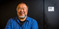 Zu sehen ist eine Portrait-Aufnahme des chinesischen Künstlers Ai Weiwei. Er trägt ein blaues Hemd und hat die Augen geschlossen
