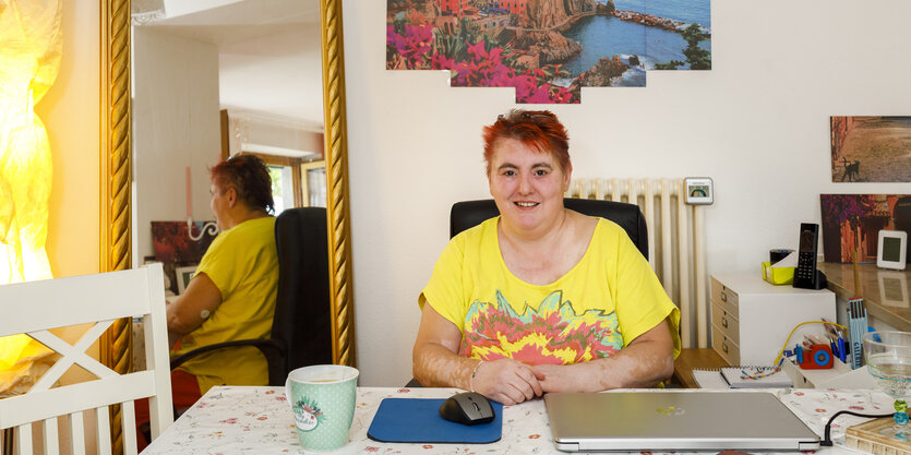 Eine Frau im gelben Shirt sitzt an einem Schreibtisch