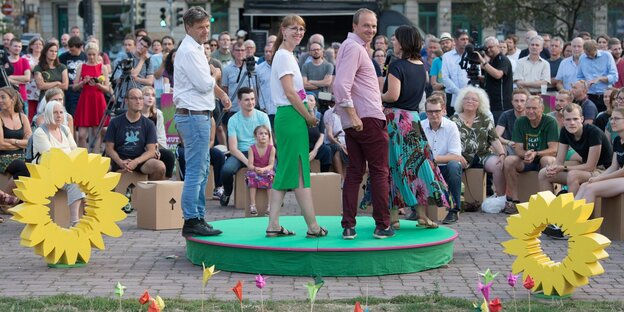 Vier Menschen auf einer kleinen, grünen Bühne Vier Menschen auf einer kleinen, grünen Bühne