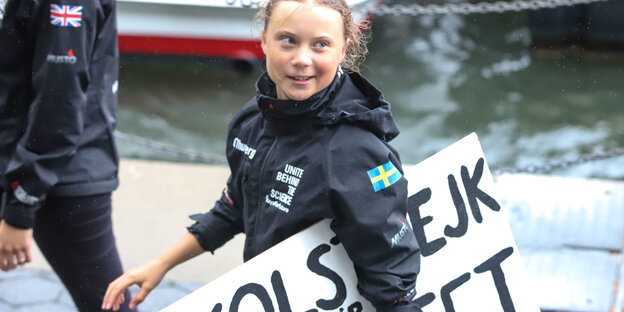 Greta Thunberg mit einem Schild unterm Arm auf dem auf Schwedisch "Schulstreik für das Klima" steht
