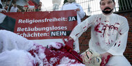 Aktivisten in weißer Kleidung demonstrieren mit viel Kunstblut gegen das Schächten
