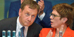 Sachsens Ministerpräsident Michael Kretschmer hält sein Ohr zur CDU-Bundesvoritzenden Annegret Kramp-Karrenbauer gewandet, während sie spricht und klatscht
