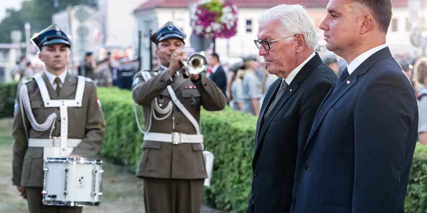 Duda und Steinmeier stehen vor einem Gedenkstein (nicht sichtbar), im Hintergrund ein Soldat mit Trommel und einer mit Trompete