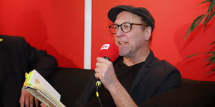 Poet Thomas Gsella bei einer Dichterlesung mit Mikrofon in der Hand