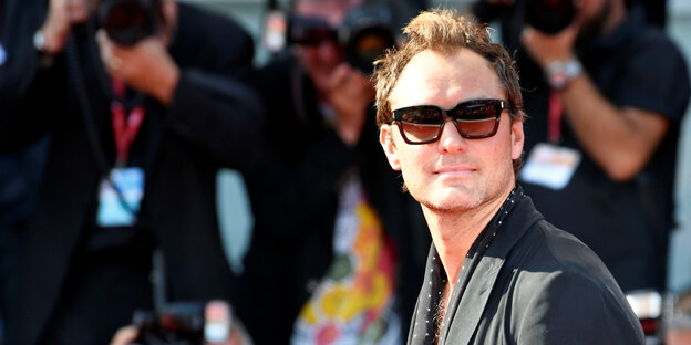 Jude law mit Sonnenbrille auf dem roten Teppich, im Hintergrund sind Fotografen zu sehen. Jude law mit Sonnenbrille auf dem roten Teppich, im Hintergrund sind Fotografen zu sehen.