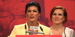 Sarah Wagenknecht spricht am Rednerpult, hinter ihr steht Katja Kipping