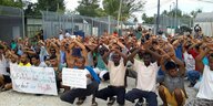 Flüchtlinge im ehemaligen australischen Internierungslager für Asylsuchende hocken mit erhobenen Armen bei einer Protestaktion zusammen