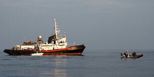 Ein Schiff im Mittelmeer, daneben patroulliert die Guardia di Finanza