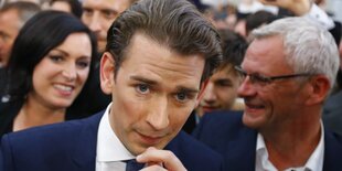 Sebastian Kurz fasst sich ans Kinn, dahinter Menschen