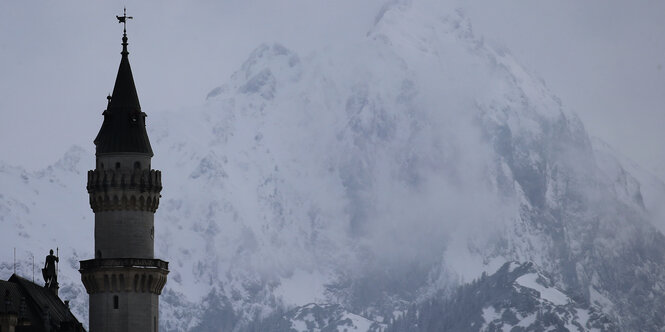 Ein Türmchen vom Schloss Neuschwanstein vor einem schneebedeckten Berg