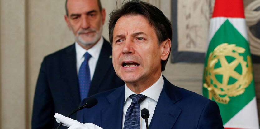 Giuseppe Conte steht an einem Rednerpult und spricht in ein Mikrofon