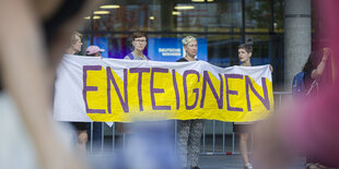 4 Personen halten ein gelbes Plakat mit der Aufschrift "Enteignen"