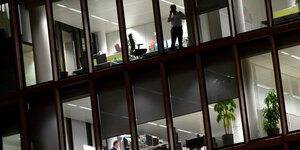Außenansicht eines Büros, durch die Glasfenster sieht man arbeitende Männer