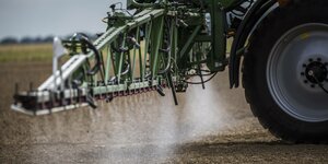 Ein Traktor mit Anhängerspritzer versprüht Pestizide