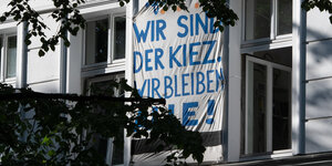 Ein Plakat mit der Aufschrift "Wir sind der Kiez. Wir bleiben alle" hängt aus einem Fenster