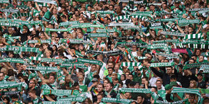 Werder Fans halten ihre Schals hoch.