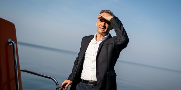 Heiko Maas beschirmt mit einer HAnd seine Augen, um in Richtung Sonne sehen zu können