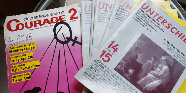 Auf dem Wohnzimmertisch liegen Zeitschriften, eine mit pinkem Cover Auf dem Wohnzimmertisch liegen Zeitschriften, eine mit pinkem Cover