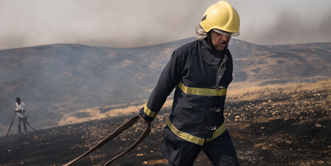 Feuerwehrmann zieht Schlauch hinter sich her