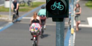 Ampel mit Fahrradsymbol steht auf grün. Im Hintergrund fahren RadfahrerInnen